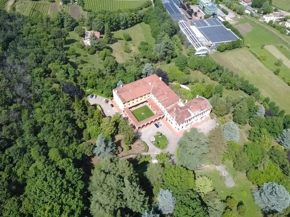 Veduta aerea zenitale di Casa del Sacro Cuore a Torreglia, circondata da giardini e alberi